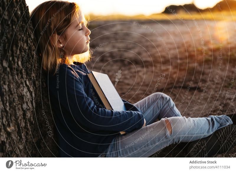 Kleines Mädchen mit Buch unter einem Baum sitzend Kind lesen Natur Feld Kofferraum Sommer lässig Windstille ruhig Frau lernen Wiese Lifestyle Literatur