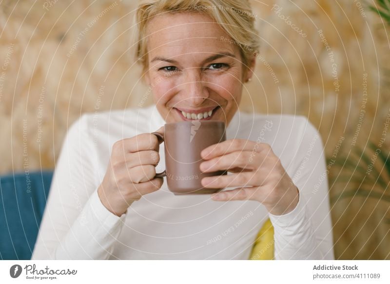 Entspannende Frau mit Kaffeetasse auf Couch ruhen Liege Business Büro Becher Kälte Getränk trinken Freizeit modern lässig Lächeln Tasse Erwachsener Innenbereich