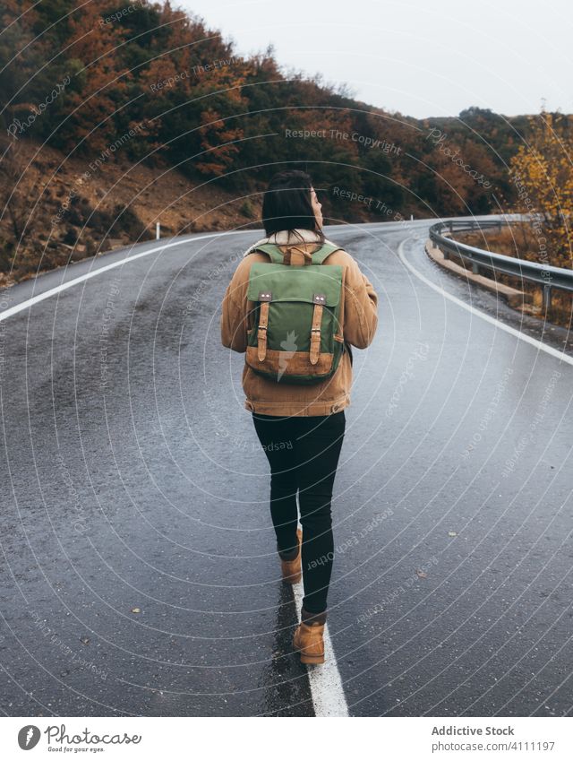 Weibliche Reisende auf Landstraße im Herbst Tag zu Fuß Frau reisen Straße Landschaft Wanderung Rucksack Natur Asphalt Wald fallen Abenteuer Freiheit Tourismus