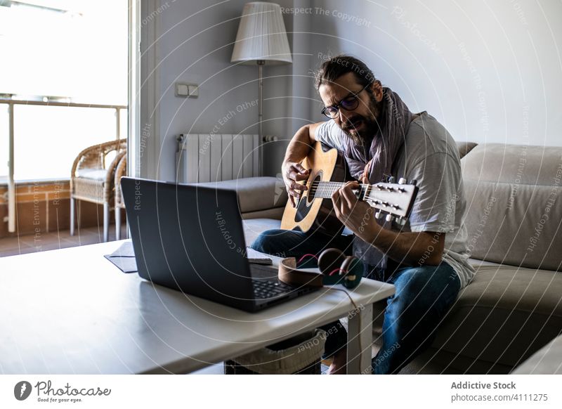 Stilvoller Gitarrist auf der Couch im Wohnzimmer Mann spielen Gitarre sitzen Liege Sofa männlich lässig Musik Songwriter Komponist Dichter heimwärts Lifestyle