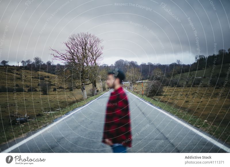 Gesichtsloser Reisender auf der Straße in ländlicher Umgebung Mann Spaziergang Natur Landschaft Abenteuer reisen Ausflug Feld leer Route wolkig bedeckt Himmel