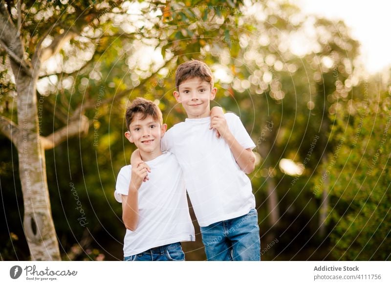 Glückliche Zwillingsjungen umarmen sich und schauen in die Kamera im Park Bruder Zusammensein Umarmen Junge Kind Lächeln Liebe Kindheit Natur gleich Sommer