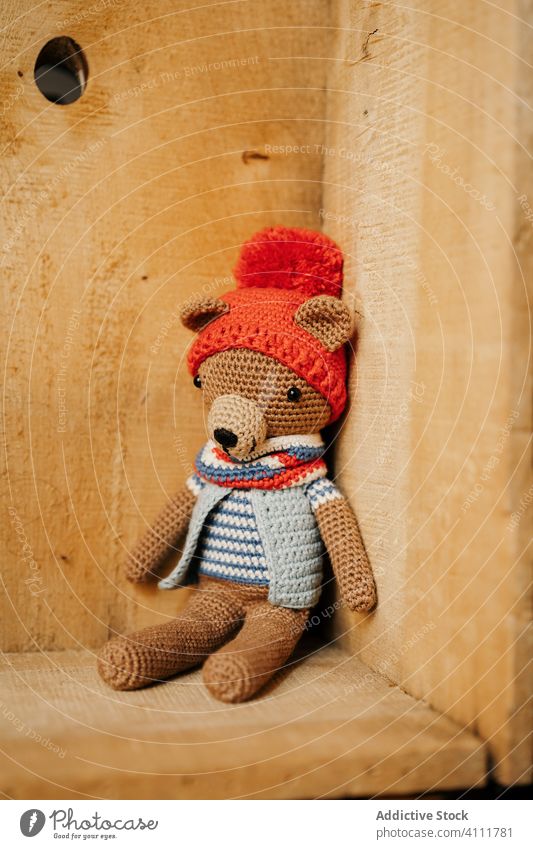 Gestrickter Bär in Holzecke Spielzeug gestrickt Eckstoß hölzern niedlich Stoff handgefertigt weich Werkstatt Kasten Wand Design farbenfroh Garn lieblich