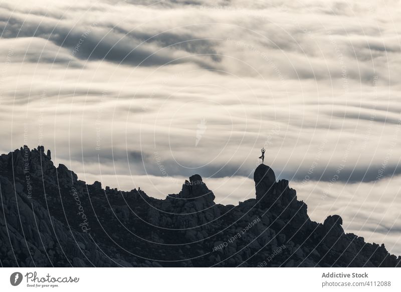 Person macht Yoga auf Berg in bewölktem Tag Landschaft Top Klippe Cloud Natur Berge u. Gebirge Felsen Himmel Anmut Silhouette Stein Gipfel Hügel Freiheit Tal