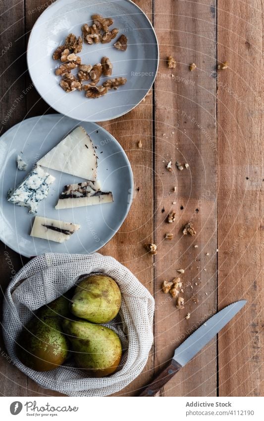 Birnen und Walnüsse neben Käse Walnussholz Messer rustikal hölzern Küche Koch organisch Feinschmecker geschmackvoll frisch lecker Lebensmittel Gesundheit