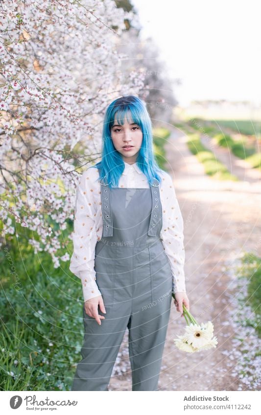 Trendige Frau im blühenden Garten Frühling Blütezeit Teenager alternativ gefärbtes Haar Blume Stil trendy modern jung blaue Haare Baum Natur geblümt schön