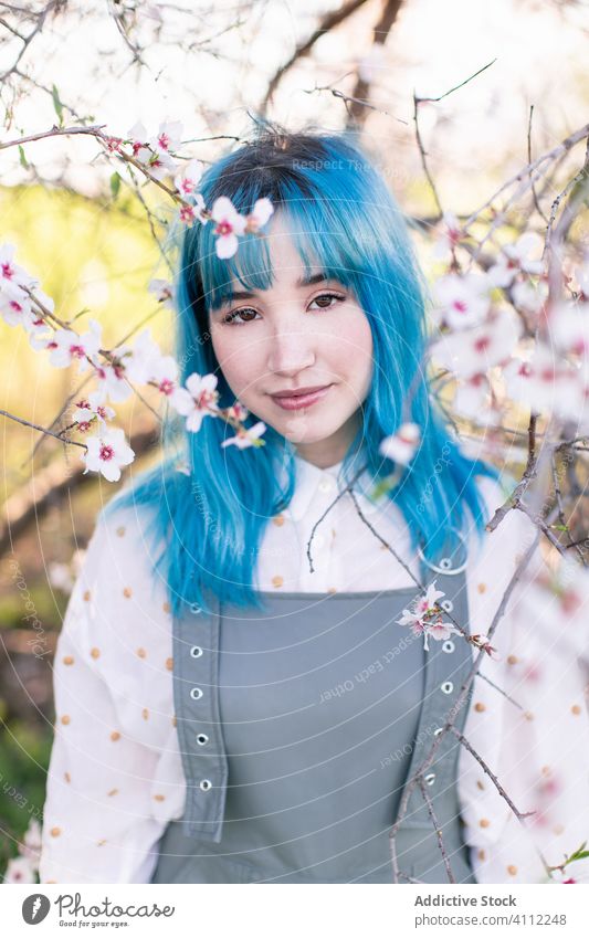 Trendige Frau im blühenden Garten Frühling Blütezeit Teenager alternativ gefärbtes Haar Blume Stil trendy modern jung blaue Haare Baum Natur geblümt schön