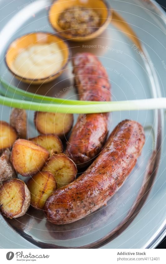 Bratkartoffeln und Würstchen mit Frühlingszwiebeln und Soßen Kartoffel Wurstwaren Grillrost Teller Kantine Saucen Schalen & Schüsseln Lebensmittel lecker