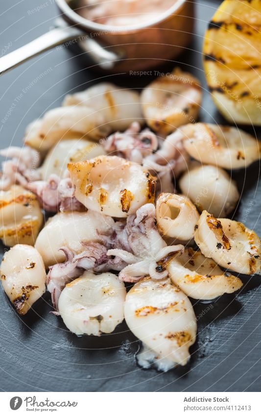 Gebratener Tintenfisch und kleine Tintenfische mit Zitrone und Soße Meeresfrüchte Grillrost Speise Tisch Café Saucen Octopus Mahlzeit lecker geschmackvoll