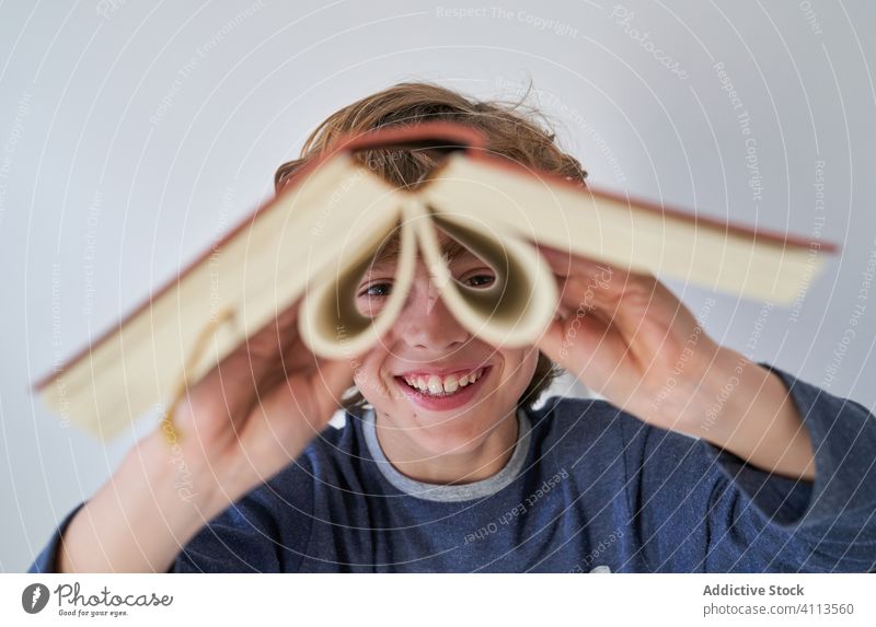 blonder Junge im Pyjama, der ein Buch als Fernglas benutzt Erkundung Fund Zukunft Fundstück Bildung Entdecker Kind Leben Blick Abenteuer wenig forschen