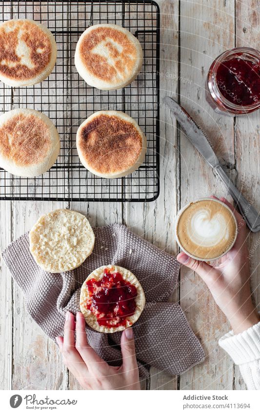 Frau beim Frühstück mit Cappuccino und selbstgebackenem Brötchen Marmelade Lebensmittel selbstgemacht frisch Tisch Hand lecker geschmackvoll Gebäck Dessert süß