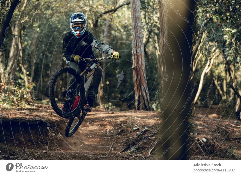 Biker in Jeans und kariertem Hemd springt mit dem Fahrrad die MTB-Strecke hinunter bergab Abenteuer professionell Berge u. Gebirge Sport Reiter im Freien