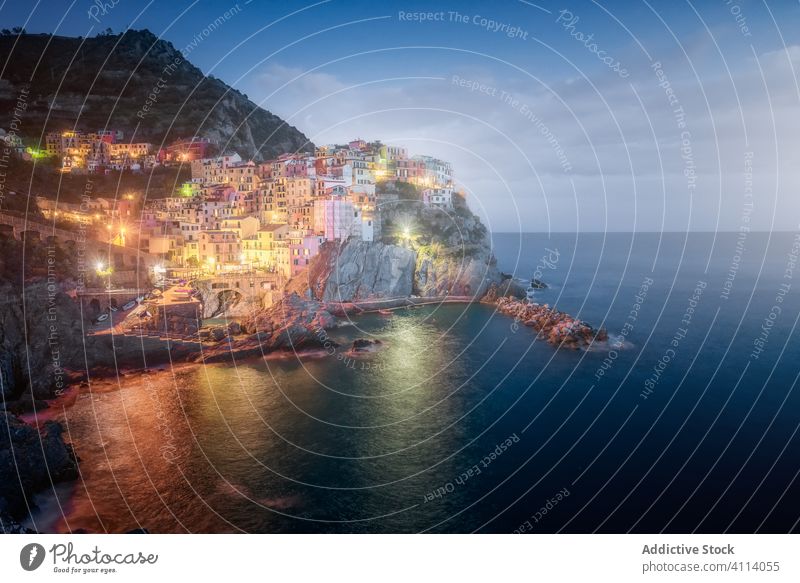 Erstaunliche Landschaft mit einer Kleinstadt mit bunten Lichtern an einer felsigen Küste, die nachts von ruhigem Ozeanwasser umspült wird Stadt MEER Nacht