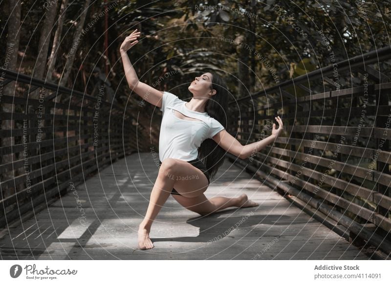 Barfuß Frau tanzt auf Brücke im Garten Tanzen Anmut Konzept jung Augen geschlossen schlank elegant ausdehnen Ballerina Park Windstille ruhig Gelassenheit