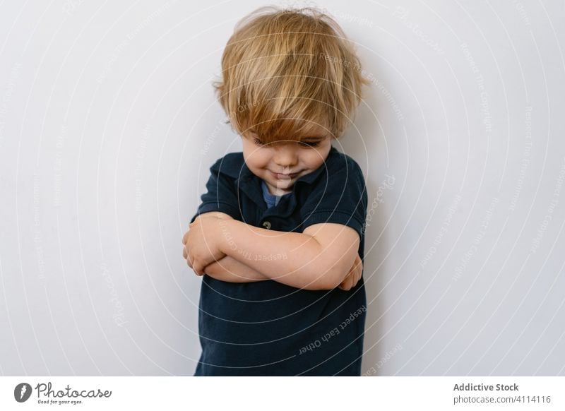 Aufgeregtes Kind mit Grimasse, das auf einer weißen Wand steht wenig Junge Vorschule Kindheit expressiv heimwärts niedlich unschuldig Sohn Textfreiraum