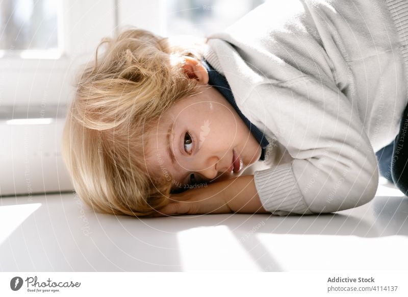 Nachdenklicher kleiner Junge auf dem Fensterbrett liegend LAZY gelangweilt charmant heimwärts allein Sonnenlicht wenig Windstille Kind besinnlich Mädchen ruhen