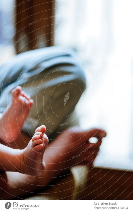 Crop-Mutter mit Baby sitzt am Fenster heimwärts ruhen Umarmung Angebot Liebe Frau Pflege Barfuß Jeanshose Stuhl Raum gemütlich Kind lässig Wochenende Windstille