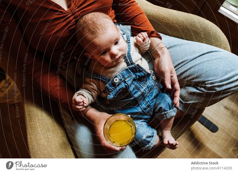 Crop-Mutter mit Saft und Baby auf einem Stuhl liegend ruhen Gesundheit gemütlich sitzen Liebe heimwärts Angebot Frau frisch trinken Getränk bezaubernd Kind