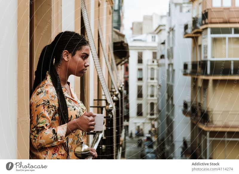 Junge Frau mit Tasse Kaffee auf dem Balkon stehend Windstille trinken lässig heimwärts ruhig nachdenklich sich[Akk] entspannen jung Afroamerikaner schwarz