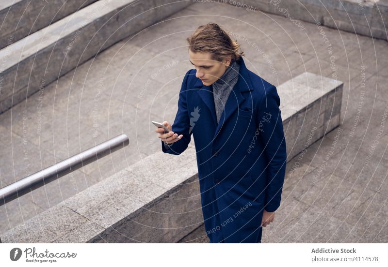 Trendiger Mann mit Smartphone in der Stadt benutzend Stil trendy ernst urban Stein Straße Apparatur Gerät Mobile Nachricht Anschluss Großstadt Browsen Internet