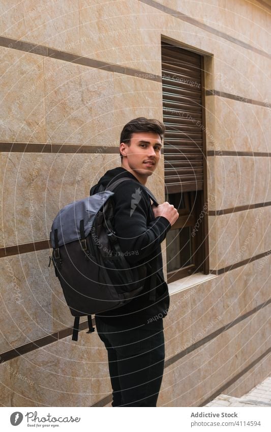 Männlicher Student auf einer Straße in der Stadt Mann Großstadt Schüler positiv Gebäude Fenster Wand Rucksack jung männlich lässig modern Lächeln Fußgänger