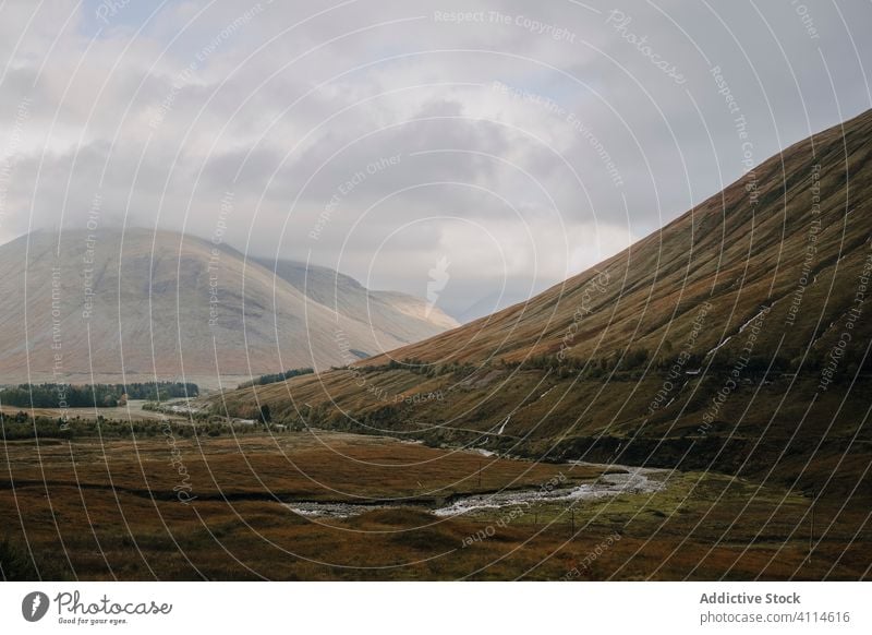 Bewölkte Landschaft mit Hügeln und Fluss Hochland bedeckt wolkig Himmel Schottland Herbst Nebel Berge u. Gebirge Gras trist Natur malerisch reisen Tourismus Tal