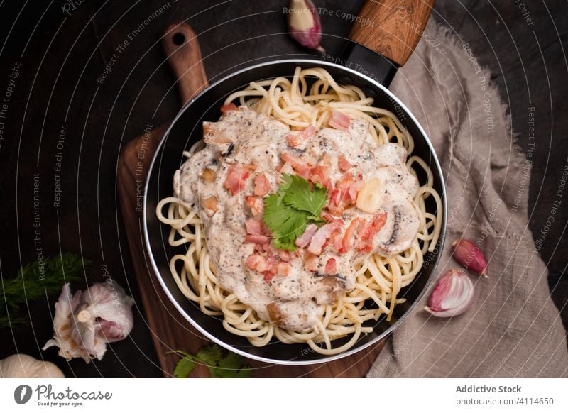 Draufsicht auf appetitliche Nudeln mit Schinken und Pilzen in Sahnesoße, serviert in der Pfanne Spätzle Saucen geschmackvoll Spaghetti Schneidebrett Gesundheit