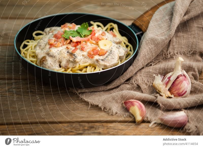 Nudeln mit Schinken und Champignons in Sahnesoße, serviert in der Bratpfanne Spätzle Pilz Saucen Pfanne geschmackvoll Spaghetti Schneidebrett Gesundheit