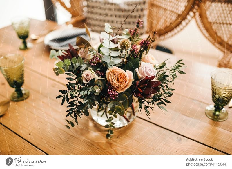 Blumen und Pflanzenzweige auf einer Vase, die einen Holztisch schmückt Haufen Blatt Blumenstrauß Wasser Blütenblatt Konzept Glas frisch Blütezeit Innenbereich