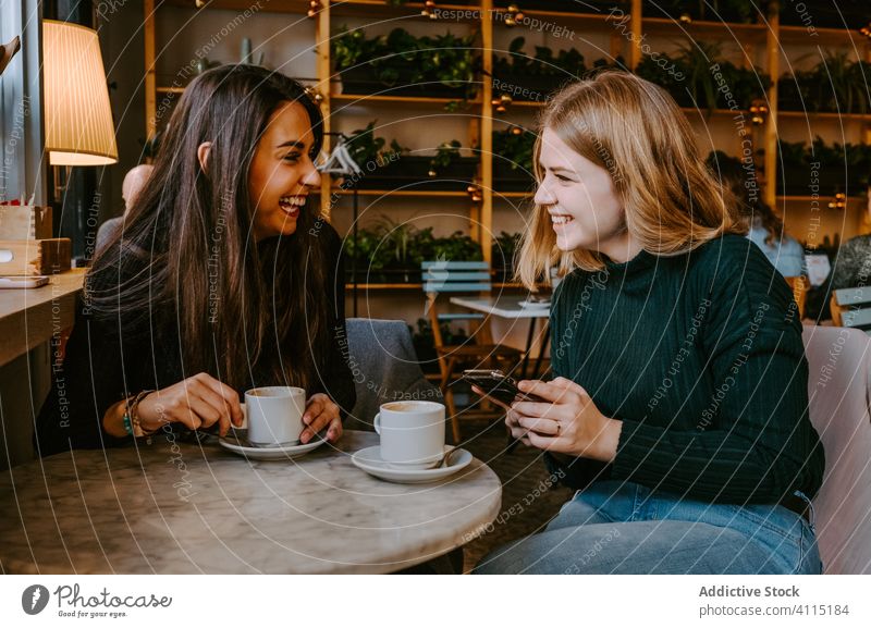 Freundinnen ruhen sich in gemütlichem Cafe aus Frauen Café Lachen Zusammensein Kaffee Smartphone benutzend Witz lässig Wochenende jung Sitzung Restaurant