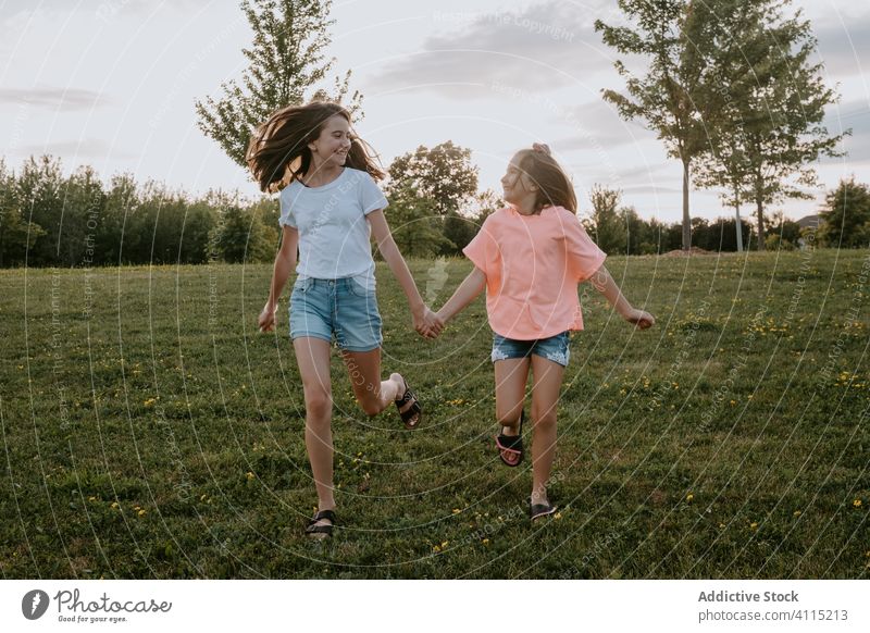 Glückliche Schwestern amüsieren sich im Sommer auf dem Land Kind Natur Zusammensein Spaß haben Mädchen Landschaft heiter laufen Teenager grün Wiese