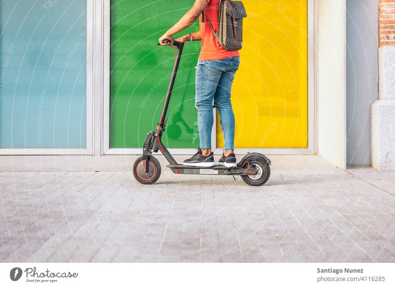 Gesichtsloser Junge, der einen elektrischen Motorroller fährt gesichtslos Reiten Afro-Look jung Mann schwarz Afroamerikaner urban Seitenansicht Elektroroller