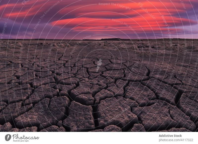 Trockenes rissiges Gelände unter bewölktem Sonnenuntergangshimmel Dürre trocknen Boden Natur wüst Land Riss heiß Ökologie flau Himmel Hintergrund Textur