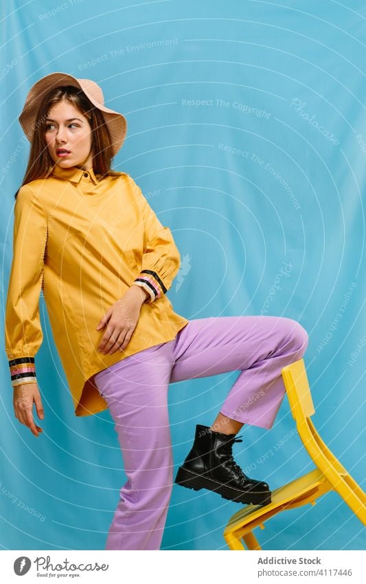 Stilvolles weibliches Modell in bunter Kleidung Frau trendy farbenfroh Outfit jung selbstbewusst Farbe retro Hut Sommer sinnlich urban Stiefel ernst stehen hell