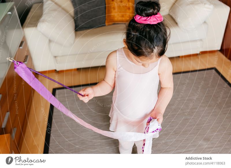 Kleine Turnerin übt mit Band zu Hause Mädchen gymnastisch Tanzen Probe heimwärts Bändchen rhythmisch spinnen Training wenig Trikot Strumpfhose Wohnzimmer Kind