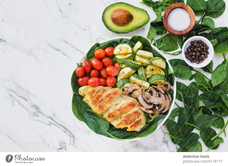 Gebratenes Hähnchen mit verschiedenen Gemüsesorten Salatbeilage Gesundheit Speise Zucchini Pilze Spinat Tomate Avocado Gewürz Gabel Zusammensetzung