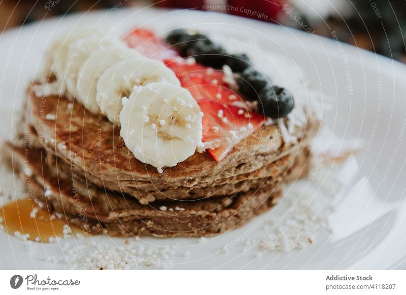 Pfannkuchen mit Banane und Erdbeeren mit Heidelbeeren und Kokosnuss dekoriert Frühstück süß dienen Tisch Blaubeeren Schuppen Diät Teller Stapel geschmackvoll