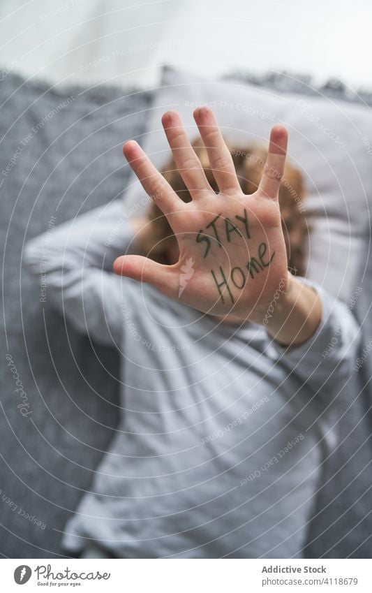 Anonymer Junge bittet darum, zu Hause zu bleiben Quarantäne zu Hause bleiben stoppen Konzept Pandemie gestikulieren Symbol Lügen Stock Decke Kopfkissen Kind