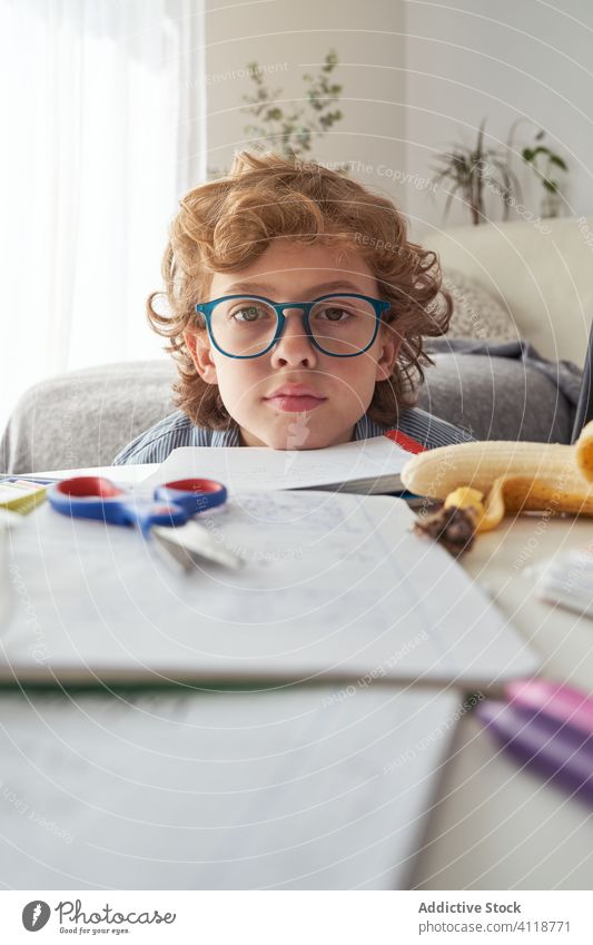 Junge macht Hausaufgaben am runden Tisch heimwärts lernen schreiben Notizblock Wohnzimmer klug Kind Komfort Sofa Liege lässig elementar Quarantäne