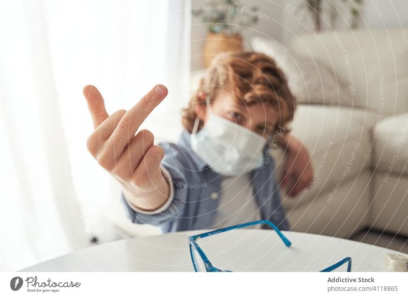 Junge zeigt Mittelfinger während der Quarantäne gestikulieren heimwärts medizinisch Mundschutz Pandemie Coronavirus ficken verhindern modern Kind behüten