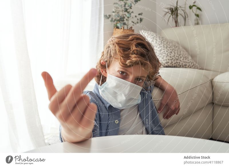 Junge zeigt Mittelfinger während der Quarantäne gestikulieren heimwärts medizinisch Mundschutz Pandemie Coronavirus ficken verhindern modern Kind behüten