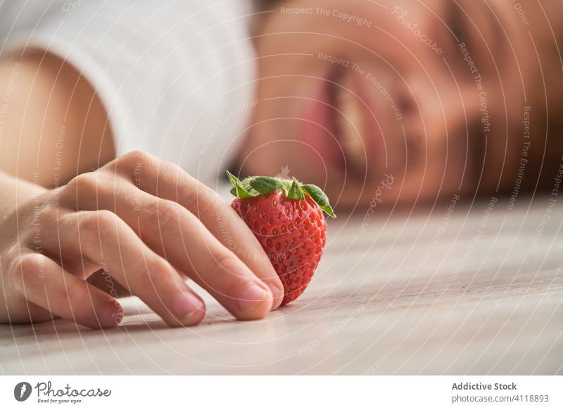 Glückliches Kind spielt mit Erdbeere auf dem Boden Erdbeeren spielen Stock heimwärts Sommer Wochenende ruhen reif Lügen heiter Lebensmittel Frucht Beeren