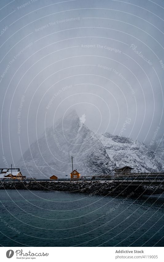 Malerische Landschaft mit Stadt am Seeufer unter grauem Himmel im Winter Hafengebiet Haus Wasser Township Dorf Ufer malerisch idyllisch ruhig Küste lofoten