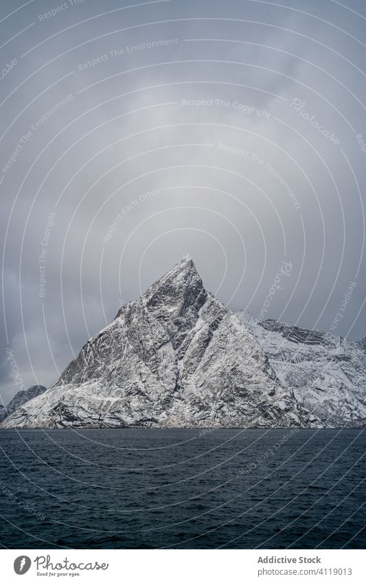 Erstaunliche Landschaft mit schneebedeckten Felsen an der Meeresküste bei bewölktem Wintertag MEER Küste Cloud Kamm Berge u. Gebirge Wasser Schnee Himmel