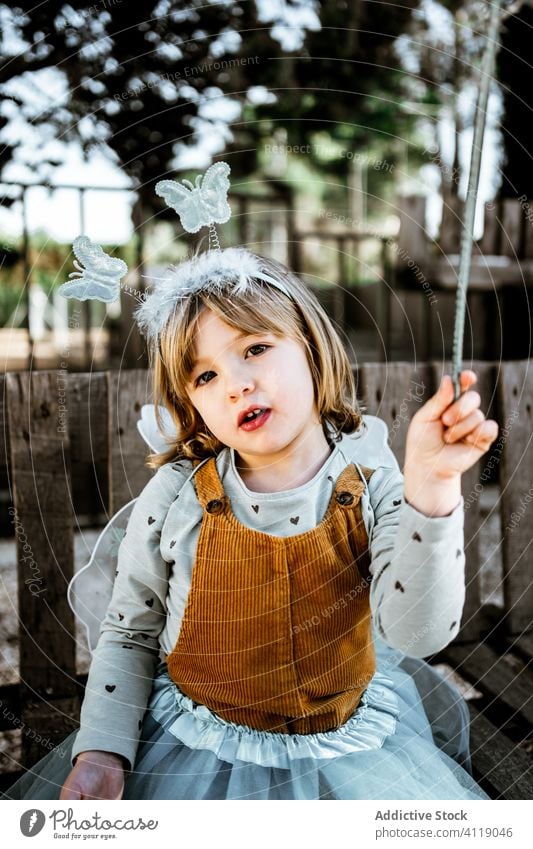 Kleine Fee sitzt im Hof Mädchen Tracht Bank sitzen schäbig niedlich wenig spielen bezaubernd Kind Park Kindheit Garten verwittert Maskerade sich[Akk] entspannen