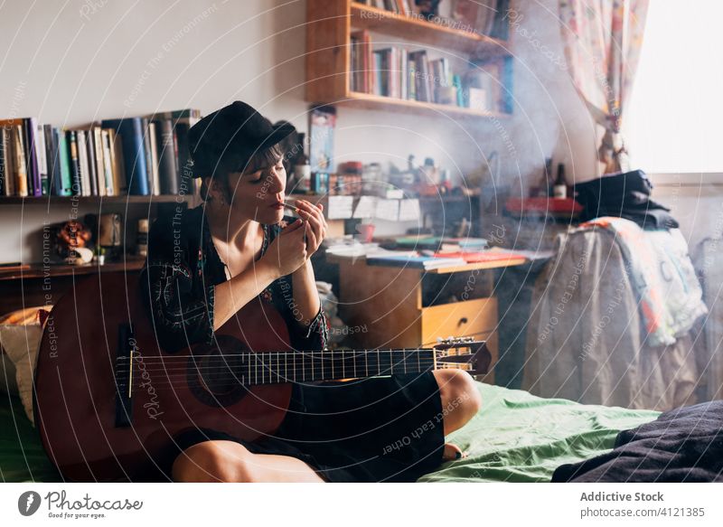 Weiblicher Hipster mit Akustikgitarre, der zu Hause kifft Rauch Unkraut Frau Gitarre akustisch sich[Akk] entspannen Marihuana Gitarrenspieler heimwärts Musik