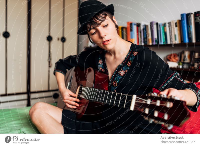 Ruhige Frau spielt Gitarre im Schlafzimmer spielen Musik akustisch Instrument Windstille ruhig trendy Melodie Klang Bett sitzen Hobby Musiker Gesang