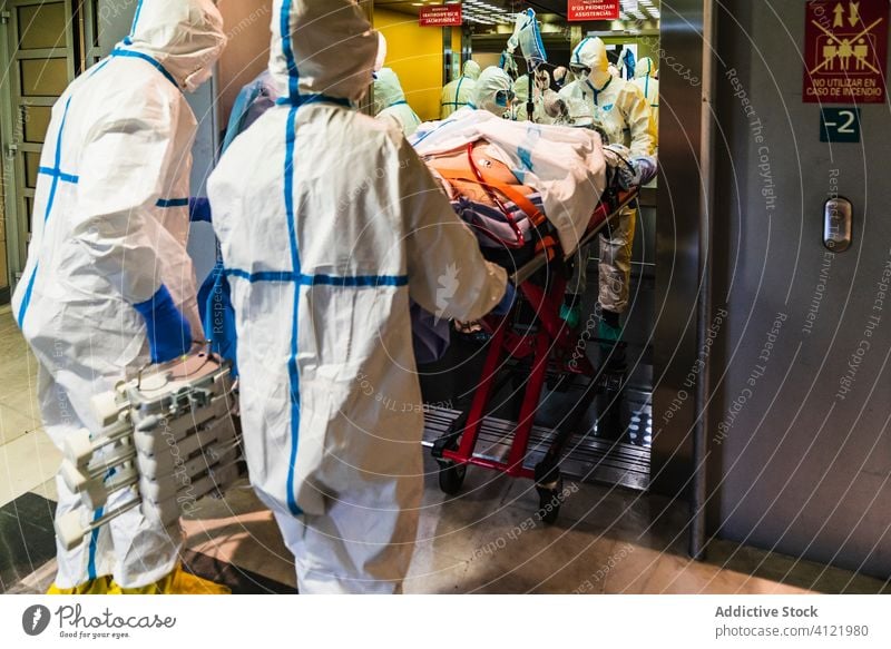 Gruppe von Ärzten in Schutzuniform bei der Entnahme des Patienten aus dem Aufzug Menschengruppe Arzt Klinik geduldig Uniform Fahrstuhl Krankenhaus