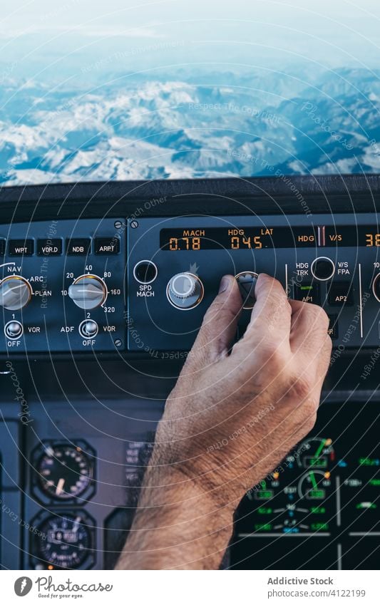 Pilot bei der Arbeit mit der Steuerkonsole während des Fluges Cockpit arbeiten Mann Hand Schalter Flugzeug Kontrolle Armaturenbrett Felsen Berge u. Gebirge