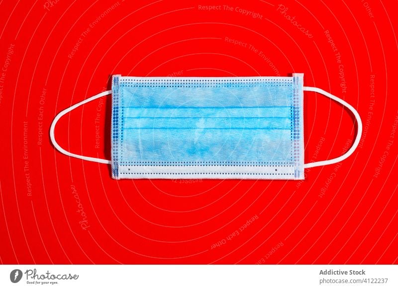 blaue Einwegmaske zum Schutz vor Viren auf rotem Hintergrund Coronavirus Seuche Gesundheit Quarantäne Infektion Krankenhaus Virus Pandemie medizinisch Krankheit